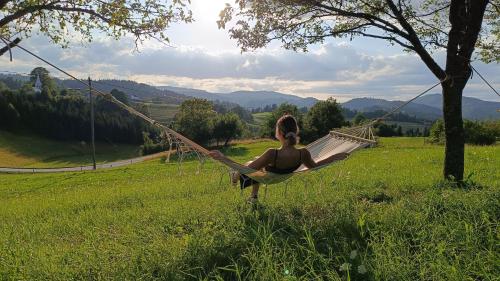 a woman sitting on a hammock in a field at Tourist Farm Strle With Great Local Food in Cerknica
