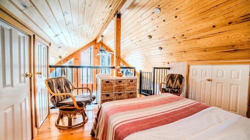 a bedroom with a bed and two chairs in a cabin at Muskoka Lakefront 3-bdrm Chalet in Port Carling