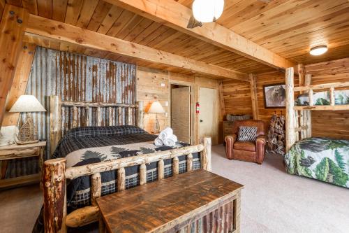 ein Schlafzimmer in einem Blockhaus mit einem Bett und einem Tisch in der Unterkunft New Listing, Red Rock Lakeview - Stunning Mountain & Lake Views! Sleeps 8 in Island Park