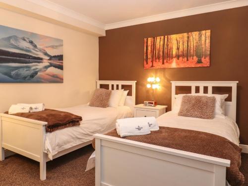 a bedroom with two beds and a painting on the wall at 5 Ladstock Hall in Keswick