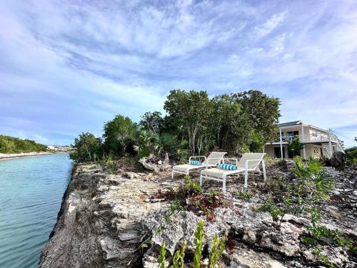 two chairs and a house on the edge of a river at Entire Waterfront House in Turtle Cove