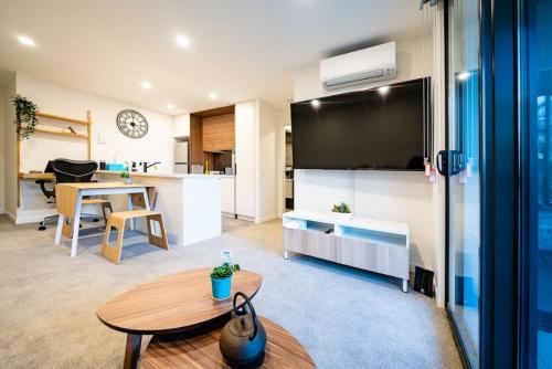 uma sala de estar com uma grande televisão e uma mesa em Luxury and Stylish Apt on NB Ave em Canberra