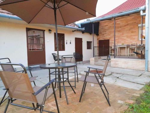 a patio with a table and chairs and an umbrella at Neubauer Vendégház*** Mohács in Mohács