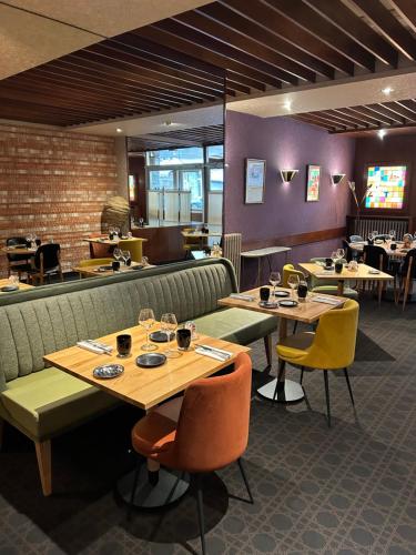 un restaurant avec des tables, des chaises et des tables en bois dans l'établissement Cit'Hotel L'Etape, à Saint-Flour