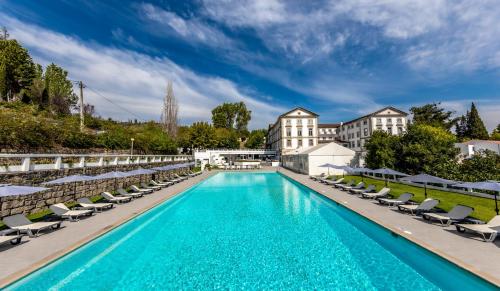 uma piscina com espreguiçadeiras e um hotel em Grande Hotel das Caldas da Felgueira nas Caldas da Felgueira