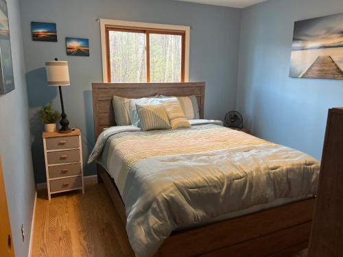 a bedroom with a bed with a nightstand and a window at Tibbets Lake House in Traverse City