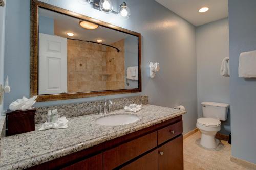 een badkamer met een wastafel, een toilet en een spiegel bij Inn of the Four Winds Seaside Oceanfront in Seaside