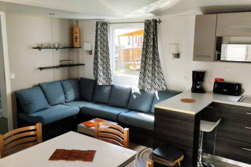 Il comprend un salon avec un canapé bleu et une cuisine. dans l'établissement Mobil-home FO 18 à Vias, à Vias
