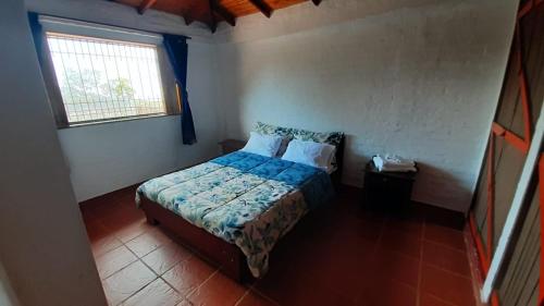 a small bedroom with a bed and a window at Increíble finca en felidia in Cali