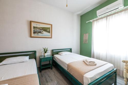 two beds in a room with green walls and a window at Galini me thea in Chrissi Akti