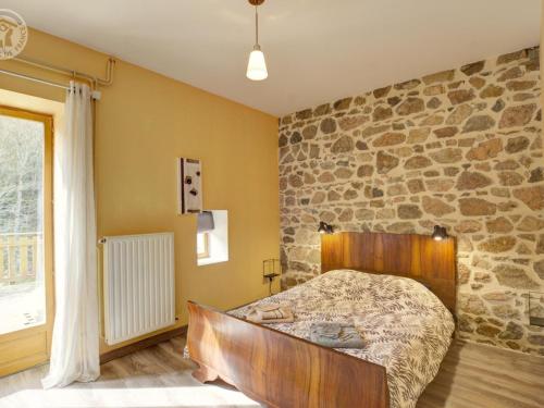 ein Schlafzimmer mit einem Bett mit einer Steinmauer in der Unterkunft Gîte Cherier, 3 pièces, 4 personnes - FR-1-496-288 in Chérier