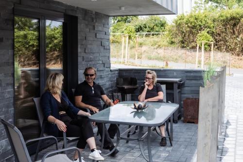 trzy osoby siedzące przy stole na patio w obiekcie Ferienwohnung am See w mieście Schwerin