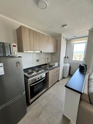 a kitchen with a refrigerator and a stove top oven at Depto hermosa vista al Lago y Volcán in Villarrica