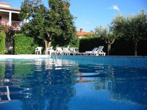 a swimming pool with white chairs and blue water at Residence Lorena Bungalow mit Salzwasser-Pool in Porec in Poreč