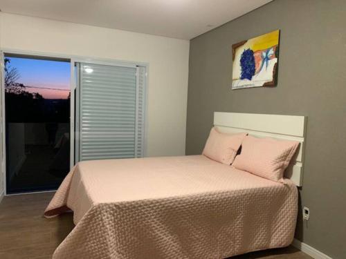 Schlafzimmer mit einem Bett mit rosa Kissen und einem Fenster in der Unterkunft Casa de Campo RSC XIII - Represa Jurumirim - SP in Paranapanema