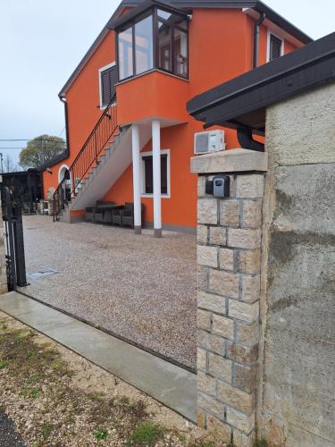 una casa naranja con una pared de ladrillo al lado en Apartment Dorina, en Buje