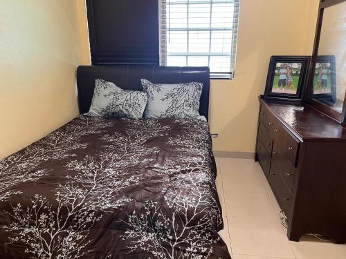 a bedroom with a bed and a wooden dresser at Krizia Place in Nassau