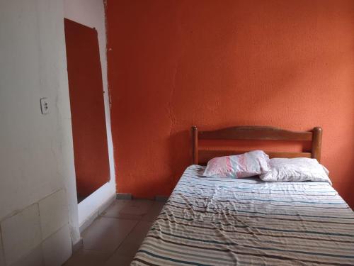 a bed in a room with an orange wall at Kit Parque Amazonia in Goiânia