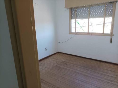 Habitación vacía con ventana y suelo de madera. en Apartamento de dos dormitorios en Santa Isabel
