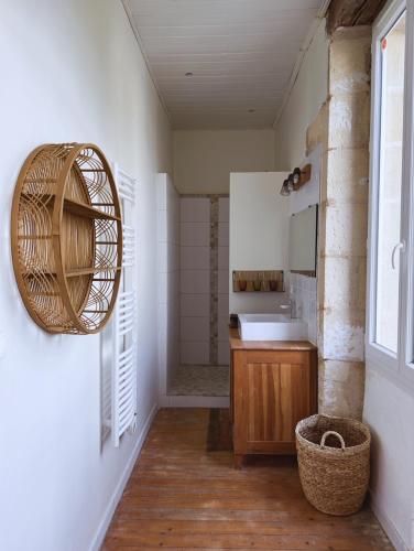 baño con lavabo y cesta de mimbre en la pared en Élégance et Charme au Cœur des Vignes - Piscine et Décoration Artisanale, en Le Pian-sur-Garonne