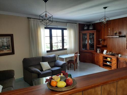Vivienda el Timón في إيخينيو: غرفة معيشة مع أريكة وطاولة مع وعاء من الفاكهة