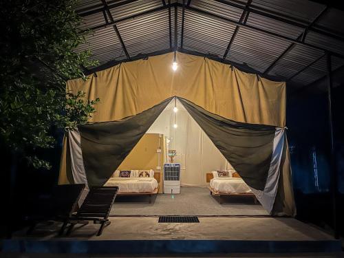 a tent in a bedroom with two beds at Glampin By Tharu Garden in Sauraha