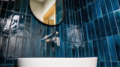 Baño de azulejos azules con espejo y lavabo en Rooms Batalogianni, en Kalambaka