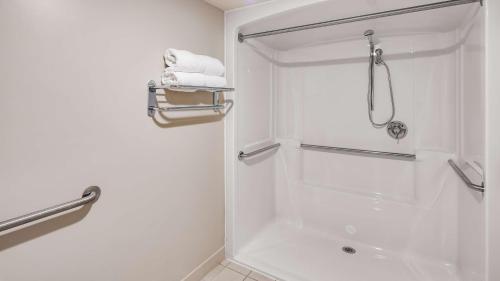 La salle de bains blanche est pourvue d'une douche et de serviettes. dans l'établissement Best Western Beacon Inn, à Grand Haven