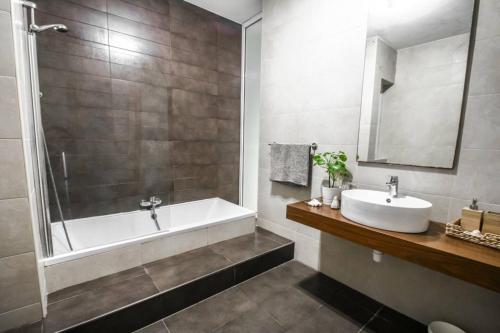 ein Badezimmer mit einer Badewanne, einem Waschbecken und einem Spiegel in der Unterkunft Duplex Apartment With Sharing Pool- Mellieha in Mellieħa