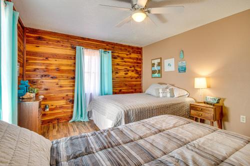 a bedroom with two beds and a wooden wall at Expansive Mountain Home Rental with Yard and Fire Pit! in Mountain Home