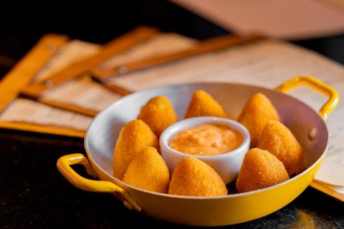 a bowl of food with a bowl of dipping sauce at Pergamon SP Frei Caneca by Accor in Sao Paulo
