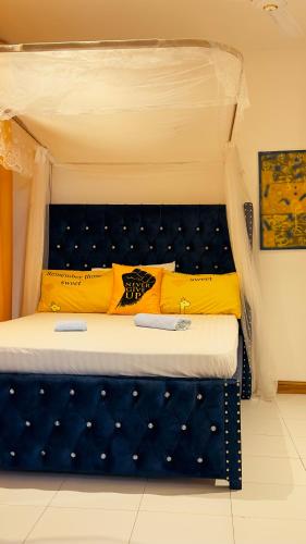 a bed with a blue headboard and yellow pillows at The pontoons in Mombasa