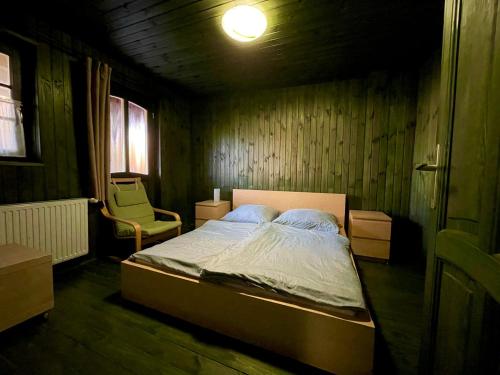 um pequeno quarto com uma cama e uma cadeira em Tündér Farm em Zirc