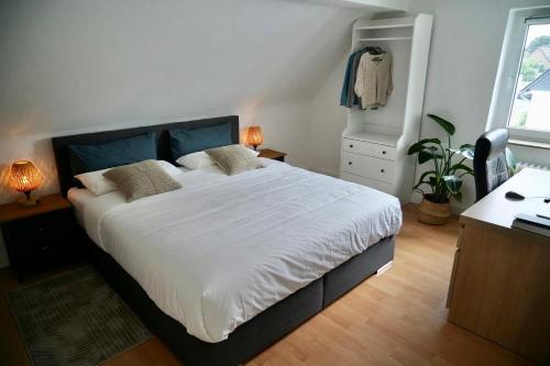 um quarto com uma cama grande e uma secretária com 2 candeeiros. em Modern 2.5 Bedroom Duplex Apartment near Messe, Airport, Arena em Dusseldorf