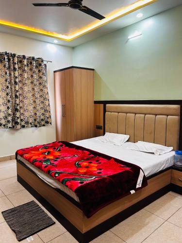 a bedroom with a large bed with a red blanket at Saraswati Dhaam in Vrindāvan
