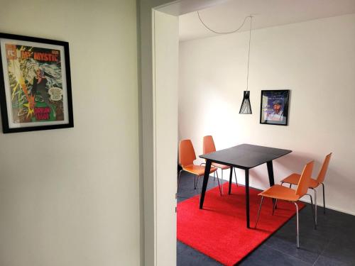 uma sala de jantar com uma mesa preta e cadeiras laranja em Get-your-flat - traumhaft niedliche FeWo 2 Zr Kü Bad, Haustier auf Anfrage, ruhig & stadtnah EG - TOP em Bochum
