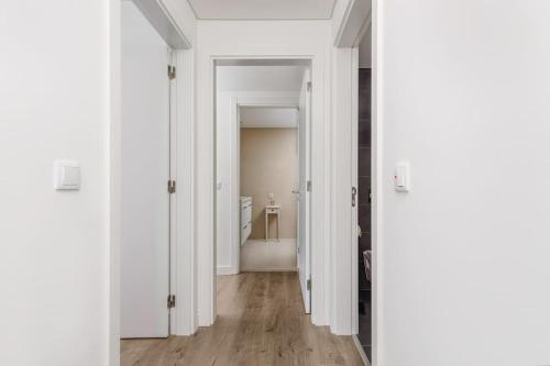 a hallway with white walls and wooden floors and a bathroom at Lisbon South Bay Seixal in Seixal