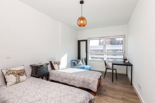a bedroom with two beds and a desk and a window at Lisbon South Bay Seixal in Seixal
