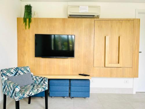a desk with a tv on a wall with a chair at Apartamento a 100 m da praia in Juquei