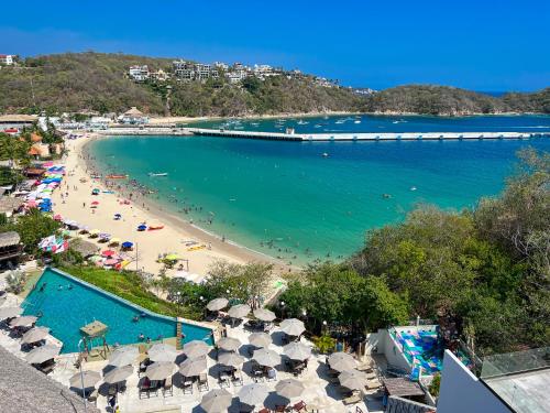 a beach with umbrellas and people in the water at Nirú Ocean Suites by Binniguenda in Santa Maria Huatulco