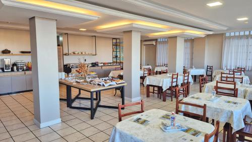 ein Restaurant mit Tischen und Stühlen und eine Küche in der Unterkunft Hotel Mont Blanc in Bento Gonçalves