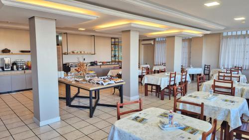 un restaurante con mesas y sillas y una cocina en Hotel Mont Blanc, en Bento Gonçalves