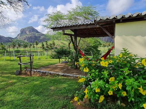 a garden with a pergola and yellow flowers at Pousada Fulô da Pedra in Serra de São Bento