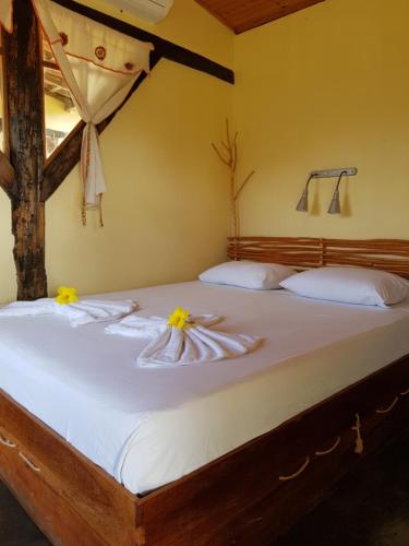 Una cama con sábanas blancas y flores amarillas. en Pousada Fulô da Pedra, en Serra de São Bento