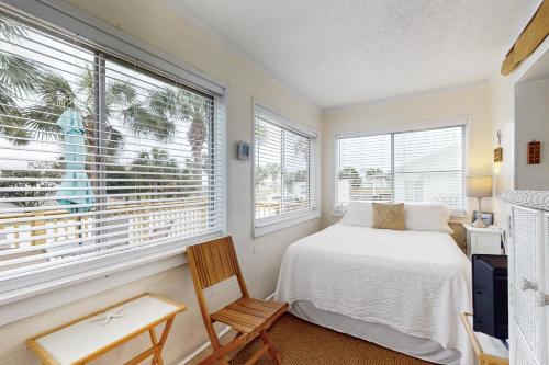 a bedroom with a bed and a chair and windows at Linda's Cozy Cottage "C" in Laguna Beach