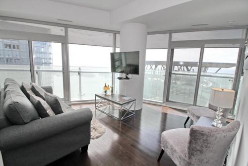 a living room with a couch and chairs and a television at Presidential 2+1BR Condo, Entertainment District (Downtown) w/ CN Tower View, Balcony, Pool & Hot Tub in Toronto
