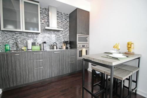 a kitchen with wooden cabinets and a counter top at Presidential 2+1BR Condo, Entertainment District (Downtown) w/ CN Tower View, Balcony, Pool & Hot Tub in Toronto
