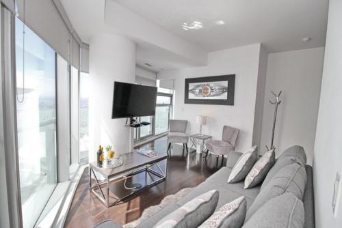 a living room with a couch and a tv at Presidential 2+1BR Condo, Entertainment District (Downtown) w/ CN Tower View, Balcony, Pool & Hot Tub in Toronto