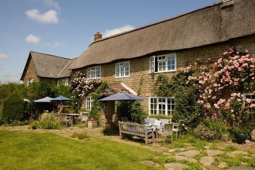 a house with chairs and umbrellas in front of it at Colly Farm in Bridport