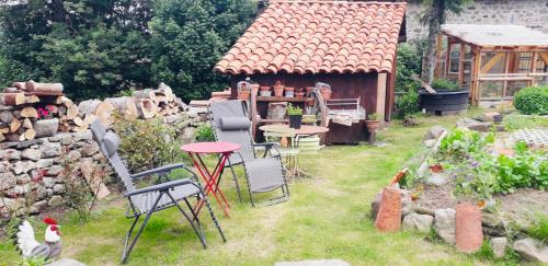 un jardín con sillas y una mesa y un edificio en Le Montadou, en Coucouron